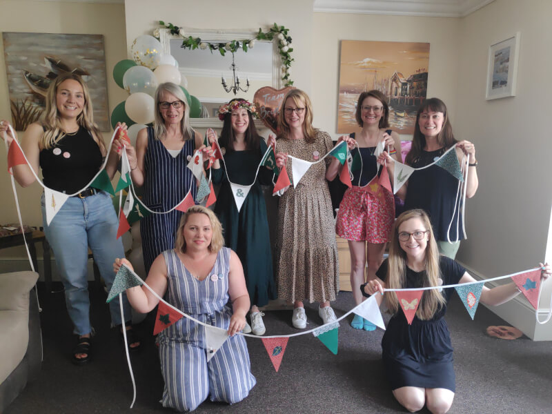 A group of people have made bunting and are holding it up for a photo